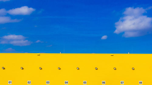 Low angle view of yellow wall against blue sky