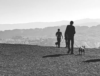 People walking with dog on mountain against sky