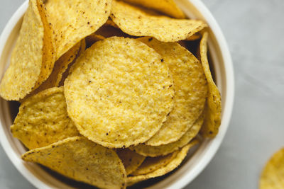 Tortilla corn chips in bowl on a gray background