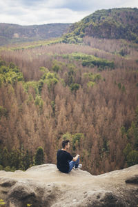 Man sitting on mountain looking at mountains