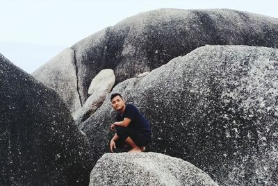 Full length of man sitting on rock
