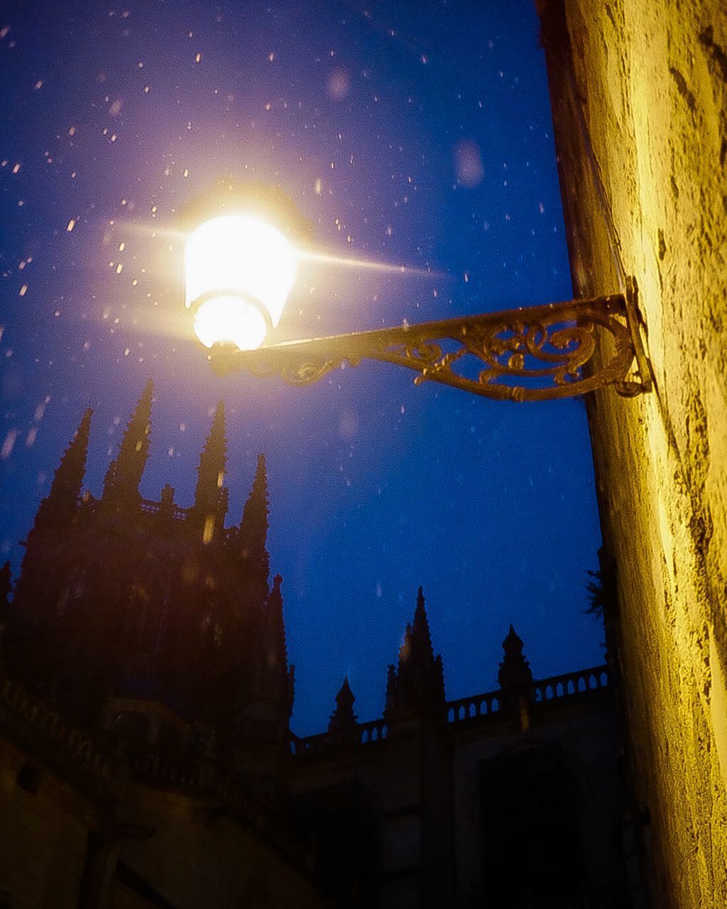 LOW ANGLE VIEW OF ILLUMINATED STREET LIGHT AGAINST BUILDINGS