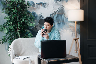 Young man using mobile phone while sitting on table