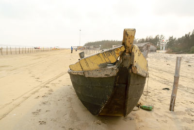 Abandoned boat moored on beach against sky