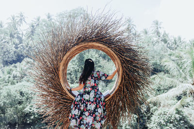 Woman standing by tree on field against sky during winter