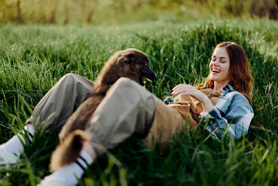 Smiling young woman with dog lying on grass