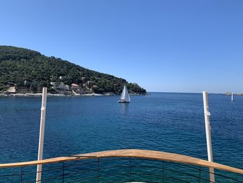 Sailboat on sea against clear blue sky