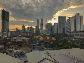 Modern buildings in city against sky during sunset