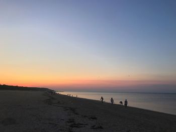 Silhouette people at beach against sky during sunset