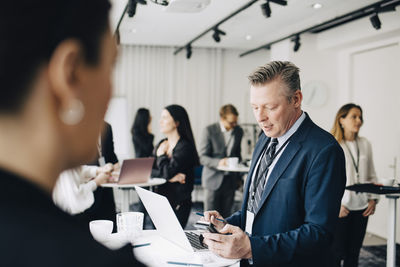 Businessman working over smart phone while standing in office seminar