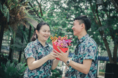 Young couple standing against trees and plants