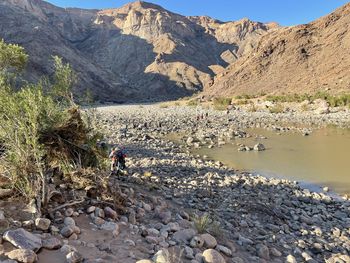 Rear view of man on rocks by mountain