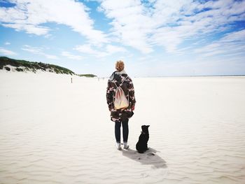 Rear view of woman walking on beach against sky