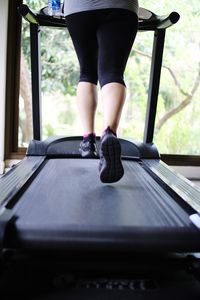 Low section of woman exercising on treadmill in gym