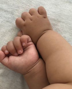 Low section of baby lying on bed