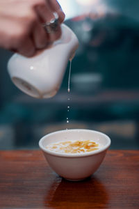 Close-up of hand pouring drink in bowl on table