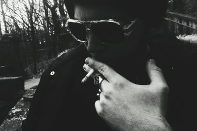 Close-up of woman holding sunglasses against sky