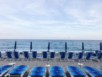 Chairs at beach against sea and sky