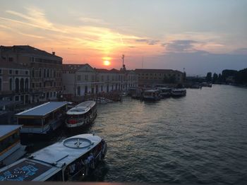Boats moored in sea against sky during sunset