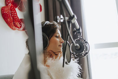 Musician recording podcast through microphone in studio