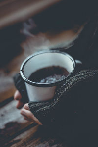 Close-up of person wearing sweater holding coffee cup