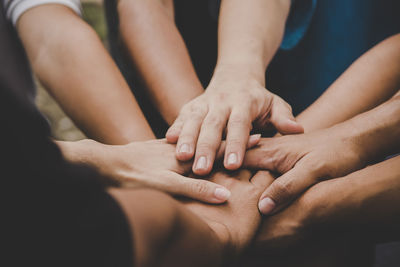 Close-up of stacking hands while huddling outdoors