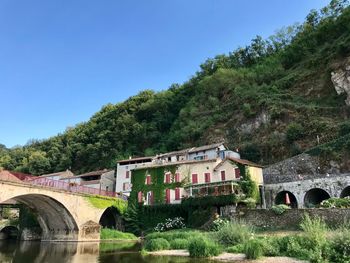 Arch bridge amidst trees and buildings against sky