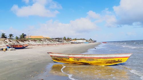 Fishing boats moored on beach against sky