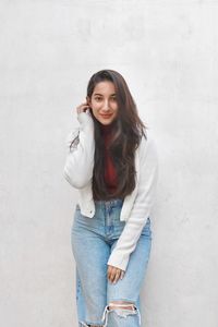 Portrait of young woman standing against wall