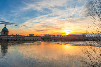 Buildings at waterfront during sunset