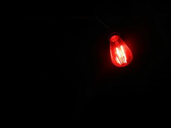 Low angle view of illuminated light bulb against black background