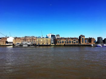 River by buildings against clear blue sky