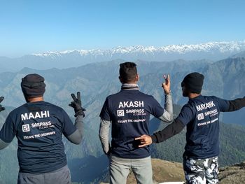 Rear view of people standing in front of mountains against sky