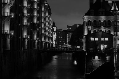 Canal amidst buildings in city at night