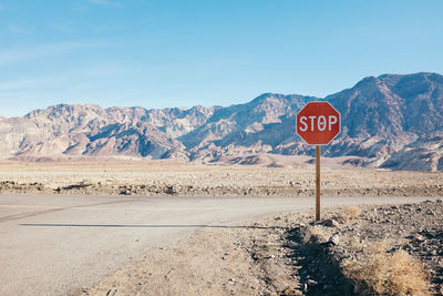 Road sign by mountains against sky