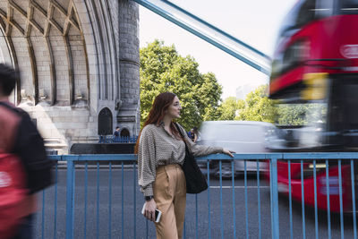 Young woman standing by railing at tower bridge, london, england