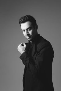 Portrait of young man standing against gray background