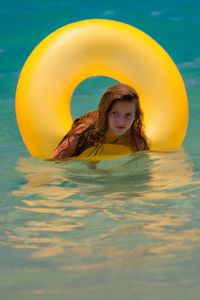 Portrait of teenage girl with inflatable ring floating on sea