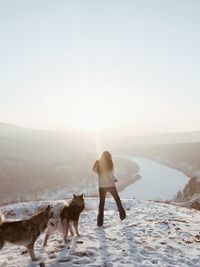 Rear view of woman with dog standing on snow