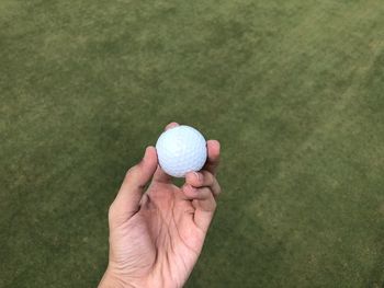 High angle view of man holding golf ball on grass field