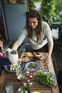 Happy woman holding jug at dining table in log cabin