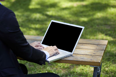 Midsection of man using mobile phone in park