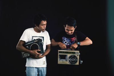 Young man holding camera over black background