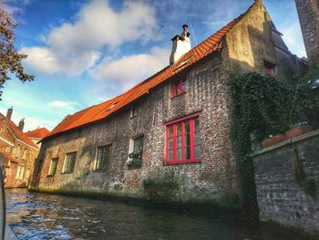Low angle view of old building by river against sky