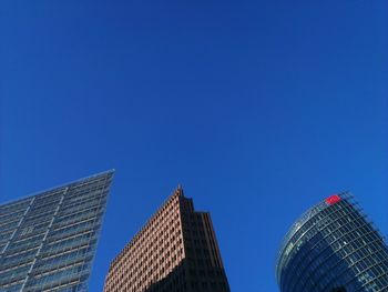 Low angle view of modern buildings against clear blue sky