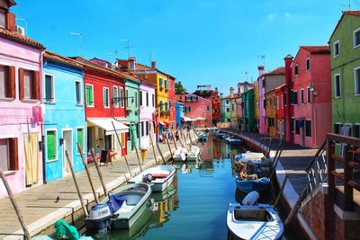 Boats moored in canal amidst buildings in city