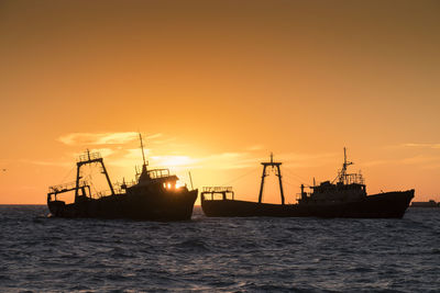 Ship wrecks at beachside at sunrise in backlight