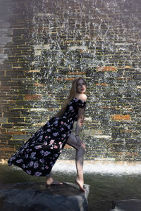 Side view of young woman against wall