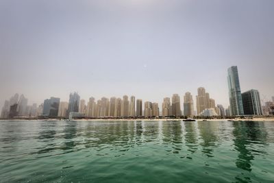 Buildings by sea against clear sky