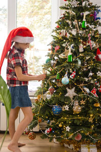 Portrait of girl playing with christmas tree at home